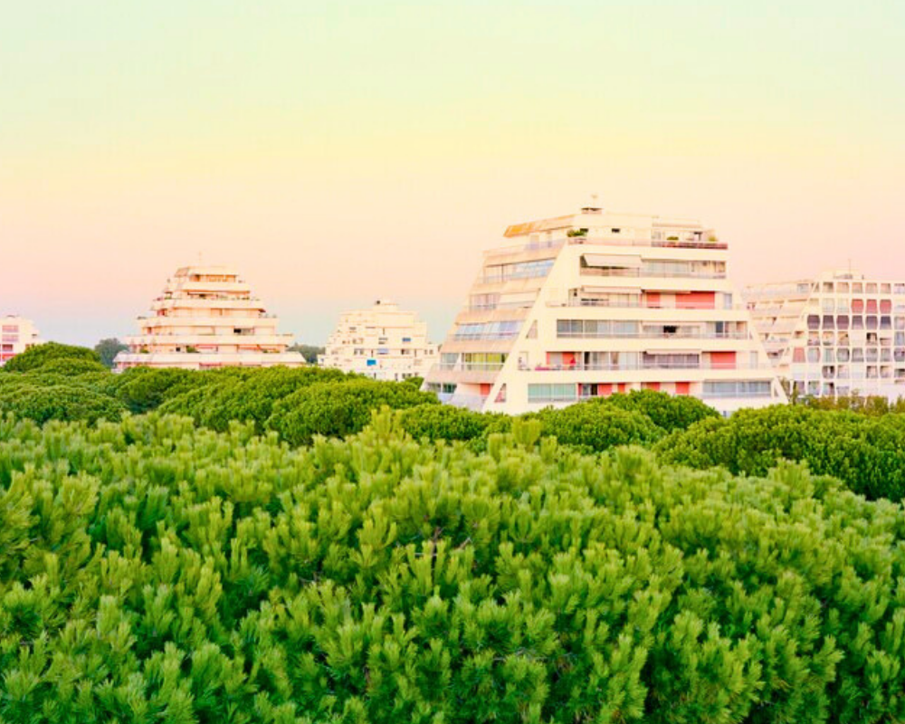 La Grande-Motte's Pyramid Buildings Integrated with the Pine Landscape Pyramid-shaped residential buildings rising above the pine forest in La Grande-Motte, illustrating Jean Balladur's vision of integrating architecture with the Mediterranean landscape.